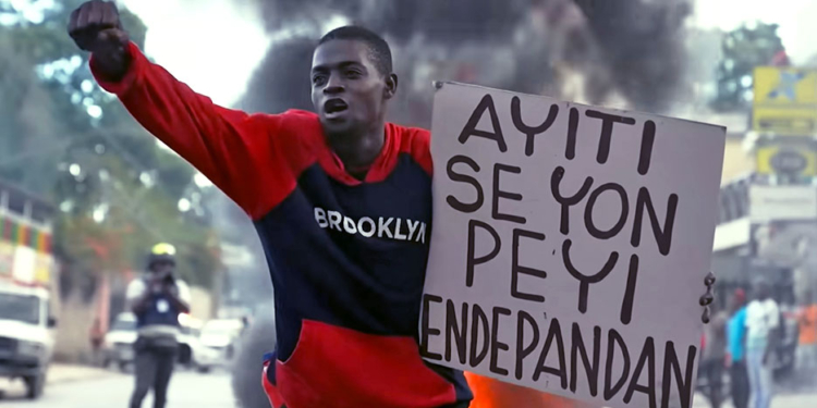 Een demonstrant met protestbord "Haïti is een onafhankelijk land"