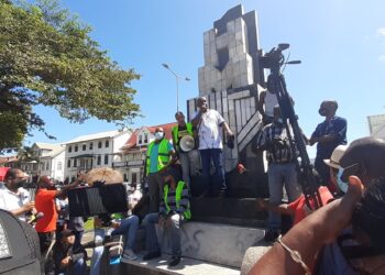 20210824 103542 scaled Verpleegkundigen van ‘s Lands Hospitaal arriveren rond half elf vanmorgen  op het Kerkplein. Gepakt en gezakt met borden en paraplu’s tegen de augustus-hitte, scanderen zij: “Weg met IMF”. Ze worden met groot applaus en gejuich ontvangen door andere leden van de vakbonden die er al zijn. De zorgsector is in ieder geval goed vertegenwoordigd tijdens het protest van de vakbonden dinsdag.