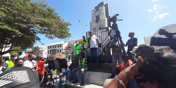 Verpleegkundigen 's Lands Hospitaal: "Weg met IMF” 1 20210824 103542 scaled Verpleegkundigen van ‘s Lands Hospitaal arriveren rond half elf vanmorgen op het Kerkplein. Gepakt en gezakt met borden en paraplu’s tegen de augustus-hitte, scanderen zij: “Weg met IMF”. Ze worden met groot applaus en gejuich ontvangen door andere leden van de vakbonden die er al zijn. De zorgsector is in ieder geval goed vertegenwoordigd tijdens het protest van de vakbonden dinsdag.