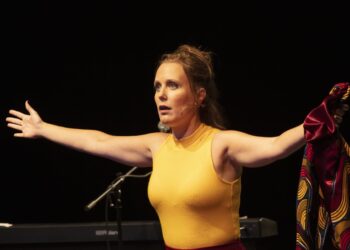 Gods Wegen Foto 3 scaled Iedereen die ooit naar het theater is geweest, weet dat  anderhalf uur zitten soms een beetje ‘saai’ of monotoon kan aanvoelen. Zeker als het gaat om een monoloog. Maar met ‘Van Gods wegen’ van theatermaakster Nina de la Parra kom je in een adembenemende rollercoaster terecht. Een stroom van woorden, muziek, de melodieuze stem van Nina, is het een permanent ‘zitten op de rand van je stoel’-soort voorstelling.
