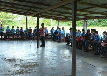 motivatiesesseie Er heerst momenteel een chaotische situatie op VOJ Marinus van Doornstraat, waarbij leerlingen bang zijn om naar school te gaan. Deze chaotische situatie ontstond, toen maandag een aantal leerlingen in trance raakte. Volgens een betrouwbare bron is sindsdien de opkomst van zowel leerlingen als leerkrachten heel slecht op school. De bron geeft aan dat maandagochtend een meisje van een  klas plotseling flauwviel. Hierna hebben leerkrachten en leerlingen geprobeerd haar wakker te krijgen, maar het lukte hen niet. De moeder van het kind, die op de hoogte werd gesteld door de leiding van de school, was snel ter plekke en nam haar mee naar huis. Enkele momenten later raakte wederom een meisje in trance. “Zij viel eerst flauw en nadat ze wakker werd, begon ze te rennen, schreeuwen, klimmen en ze wilde vechten, ze deed heel raar. Enkele leerlingen probeerden haar onder controle te krijgen, maar dat lukte nauwelijks, omdat ze met haar handen en voeten tegenstribbelde. Ze ging ook van klas tot klas en zocht naar het meisje, dat eerder flauw was gevallen en riep haar constant. Dit meisje was niet bij en er was iets op haar gekomen, want ze zei dat ze iemand gaat vermoorden.” De leiding van de school maakte contact met de ouders van dit meisje en zij werd na een tijdje afgehaald door een ouder, maar het meisje wilde de school niet verlaten. “Ze hield stevig aan de bedrading van de schoolramen vast, maar uiteindelijk viel ze flauw en een paar leerlingen tilden haar op en brachten haar naar de auto.” De leiding besloot toen om de school wat eerder te sluiten, maar er is nog een aantal leerlingen in trance geraakt, waarbij zeker twee leerlingen een heel agressieve houding vertoonden. De bron kan niet precies aangeven hoeveel leerlingen in trance zijn geraakt die dag. Sindsdien is de opkomst van zowel leerlingen als leerkrachten heel slecht op de school, omdat eenieder bang is voor deze situatie. Het is nog niet bekend welke maatregelen de Inspectie en het ministerie zullen treffen in deze serieuze situatie.