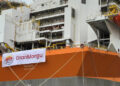 A large orange and white ship with a banner on it.