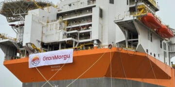 A large orange and white ship with a banner on it.