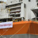 A large orange and white ship with a banner on it.