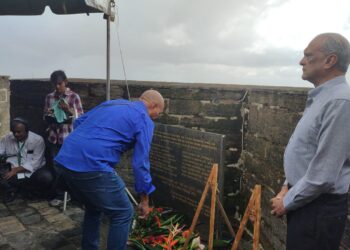 Nabestaanden tijdens de herdenking van de 8 Decembermoorden in 2023. Sunil Oemrawsingh kijkt toe terwijl er een bloemetje wordt gelegd | Foto Amanda Palis