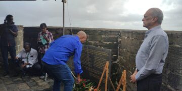 Nabestaanden tijdens de herdenking van de 8 Decembermoorden in 2023. Sunil Oemrawsingh kijkt toe terwijl er een bloemetje wordt gelegd | Foto Amanda Palis