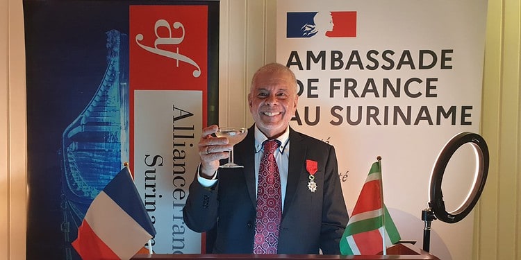 WhatsApp Image 2025 11 19 at 2.23.13 PM Met deze woorden startte dr. Ruben del Prado op dinsdagavond 18 november zijn acceptatiespeech, na ontvangst van een van de hoogste onderscheidingen van de Franse Republiek: Chevalier de la Légion d’Honneur, Ridder in het Legioen van Eer. In de residentie van ambassadeur Nicolas de Bouillane de Lacoste kreeg hij de medaille opgespeld door de Franse diplomaat, op voordracht van de Franse president Emmanuel Macron. “Voor zijn inzet voor de geneeskunde, de strijd tegen aids, de hiv-pandemie, de volksgezondheid op alle continenten en voor het opnieuw opstarten van de Alliance Française in Suriname”, lichtte De Lacoste toe, na een opsomming van Del Prado’s staat van dienst.
