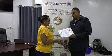LVV directeur Toekoen overhandigt een van de deelnemers aan de citrustraining haar certificaat 1536x1025 1 Jonge landbouwer Teroen Lakhai investeert in citrus en moedigt jongeren aan om klein te starten en te groeien in de landbouw. Ontdek zijn visie en kansen in deze sector in