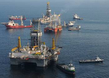 GOLFO DE MÉXICO - La unidad móvil de perforación en alta mar (MODU) Development Driller II (cerca) está lista para perforar un pozo de alivio en el lugar del Deepwater Horizon el 18 de mayo de 2010, mientras la MODU Q4000 se mantiene en posición justo encima del preventor de reventones dañado. Mientras el buque de perforación Discover Enterprise (al fondo) sigue recogiendo petróleo del conducto roto, a bordo del Q4000 se están haciendo los preparativos para la posible utilización de un «junk shot» o del método «top kill». Foto de la Guardia Costera de EE. UU. tomada por el contramaestre de tercera clase Patrick Kelley.