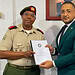 Dissertation presentation beside Suriname flag El teniente coronel Vernon W. Pengel propone reforzar la Ley de Aplicación de la Convención sobre Armas Químicas, con miras a mejores posibilidades de supervisión para la Suriname Non-proliferatie Autoriteit (Autoridad de No Proliferación de Surinam).