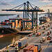 Deep-water port in Berbice: major US$ 2 billion project in 2026 9 Busy shipping port with cargo ships docked under tall cranes, surrounded by stacked containers and trucks at sunset